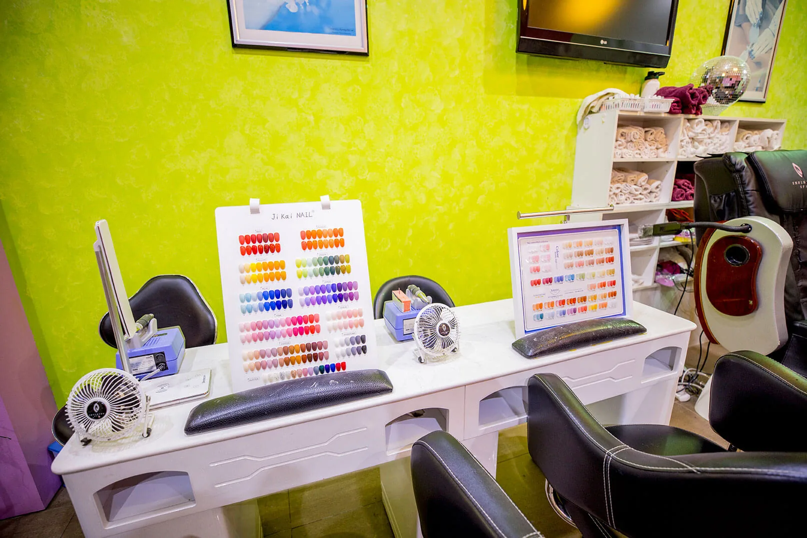 Manicure table with nail-colour swatch boards, lime feature wall and pedicure throne